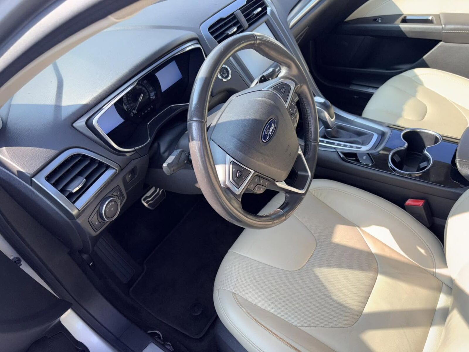 Detailed Ford sedan cabin with light leather seats and clean dashboard