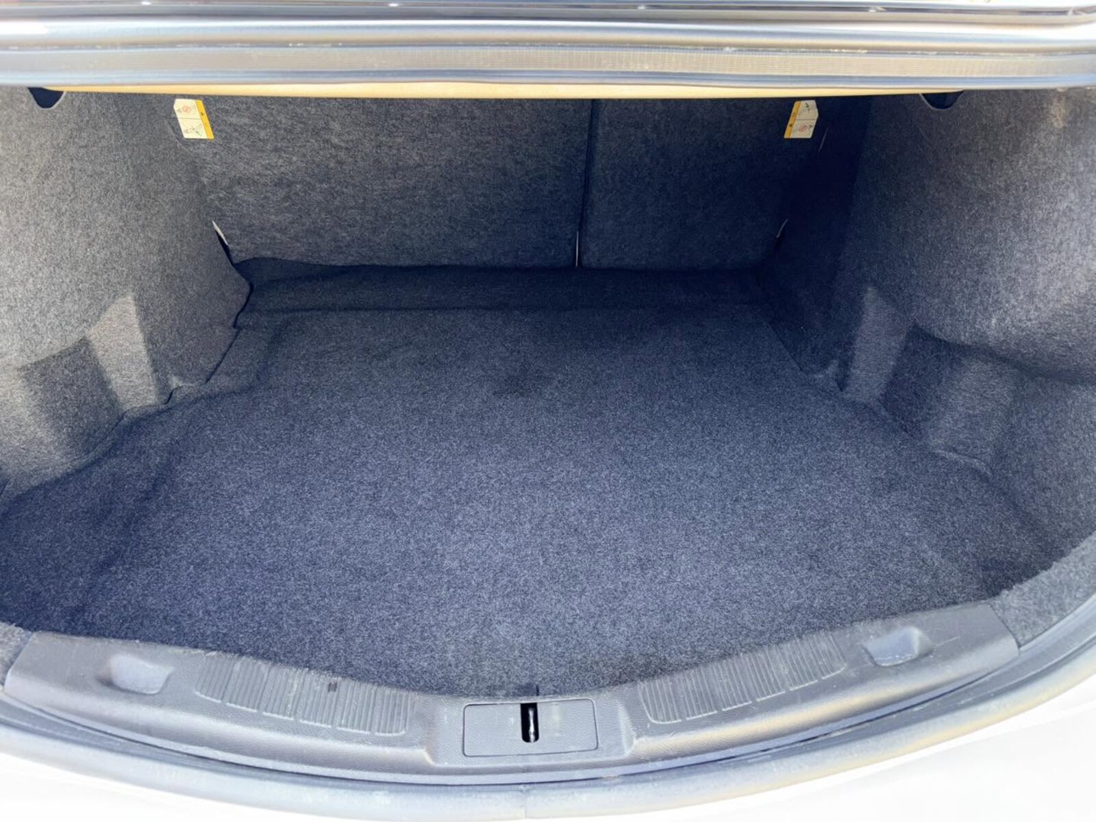 Vacuumed sedan trunk with clean charcoal carpeting